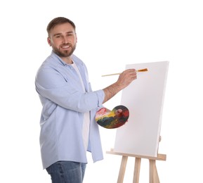 Photo of Man painting with brush on easel against white background. Young artist