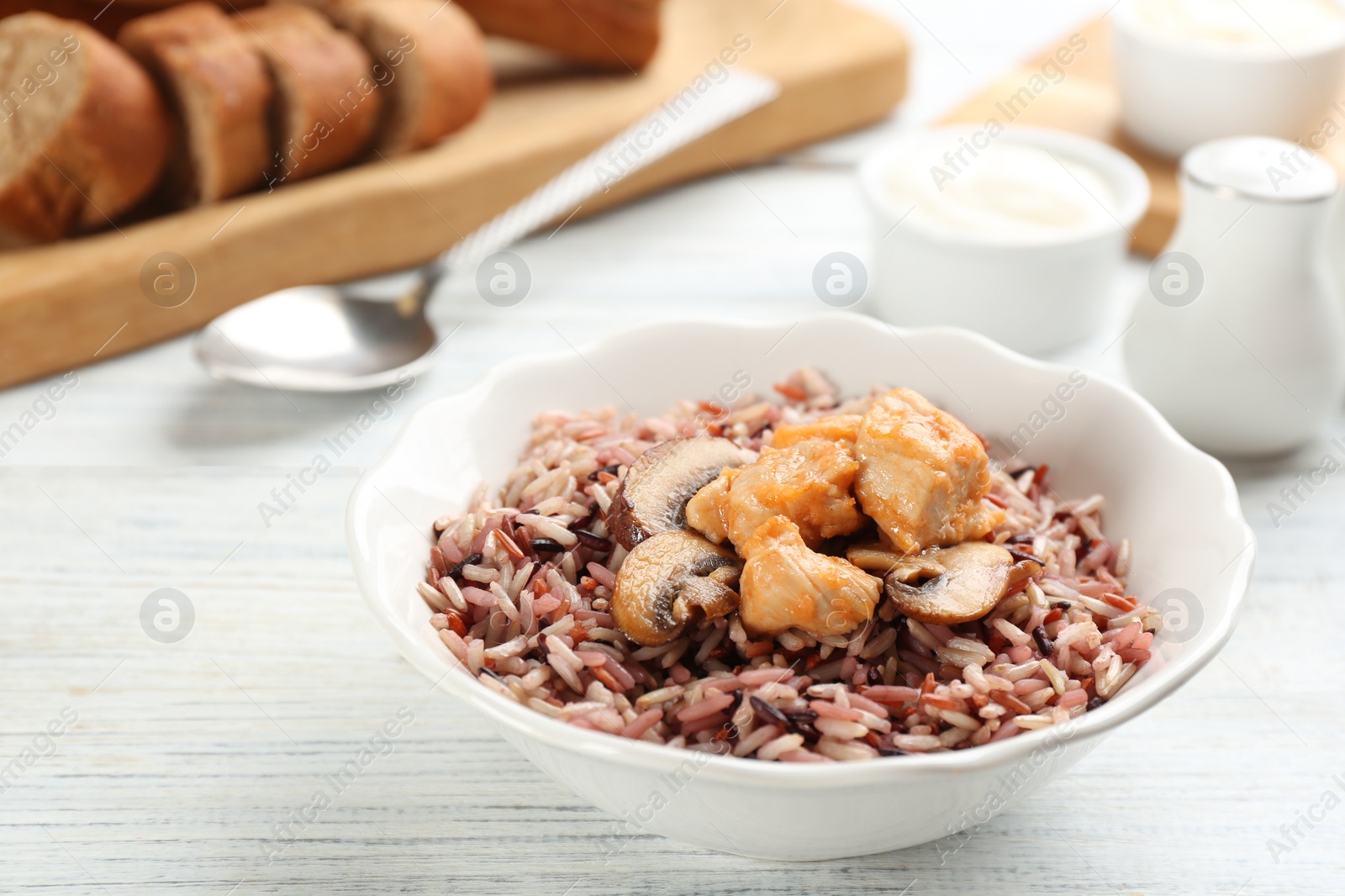 Photo of Delicious brown rice in bowl on white wooden table