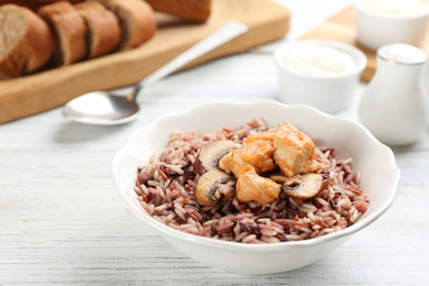 Photo of Delicious brown rice in bowl on white wooden table