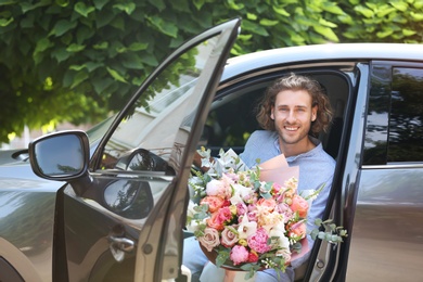 Young handsome man with beautiful flower bouquet in car