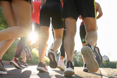 Group of people running outdoors on sunny day, closeup