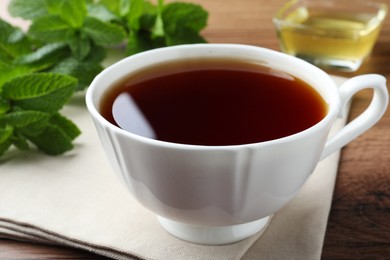 Photo of Cup of hot aromatic tea with mint on wooden table, closeup