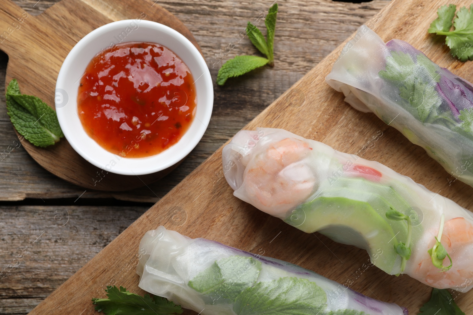 Photo of Delicious spring rolls and sauce on wooden table, top view