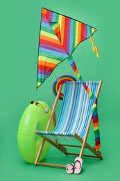 Photo of Deck chair, kite and beach accessories on green background. Summer vacation