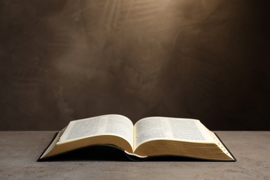 Open Bible on light grey table against brown background