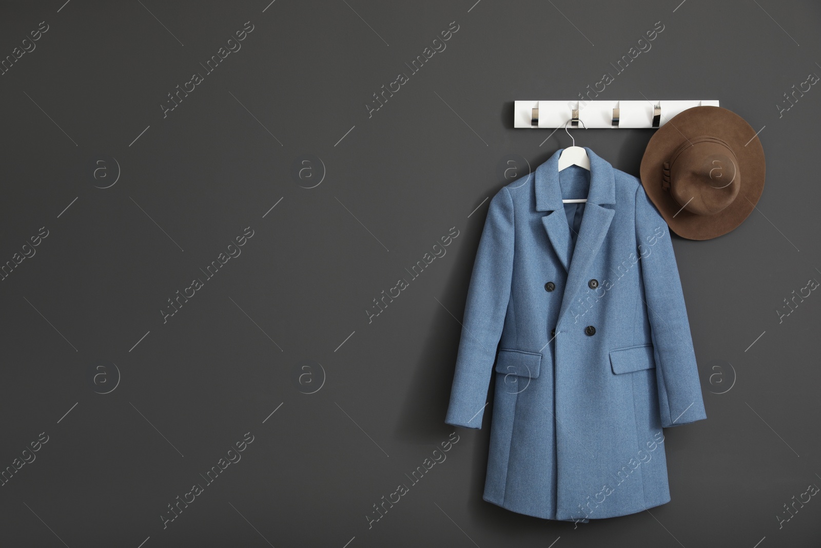 Photo of Coat and hat on wall hanger in stylish hallway interior. Space for text