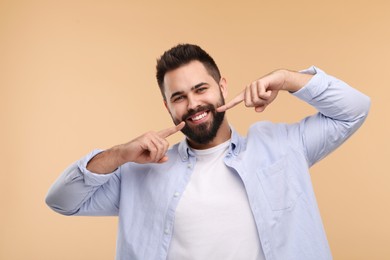 Photo of Man showing his clean teeth and smiling on beige background