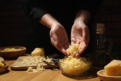 Photo of Woman with grated cheese at wooden table, closeup