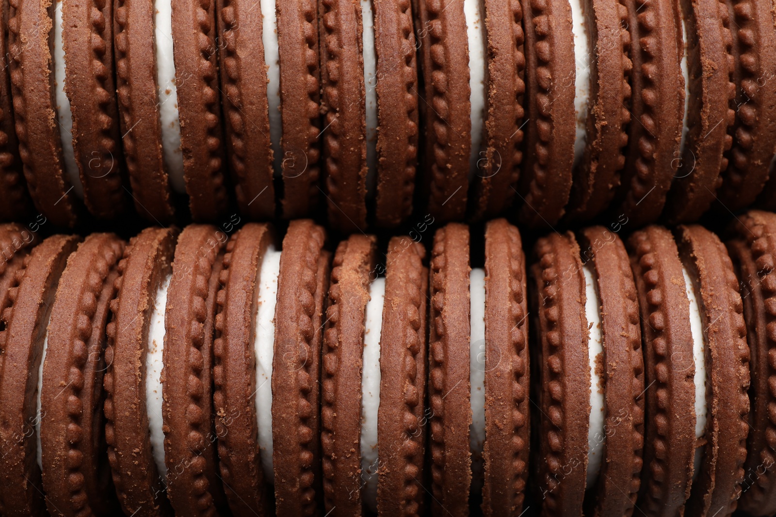 Photo of Tasty chocolate sandwich cookies with cream as background, closeup