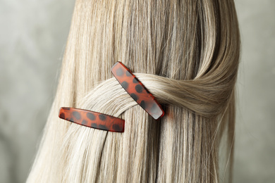 Photo of Young woman with beautiful hair clips on grey background, closeup