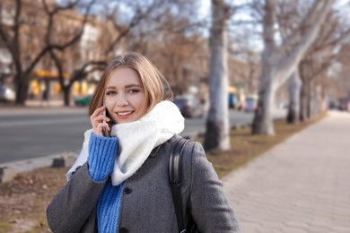Photo of Portrait of happy young woman talking on phone outdoors