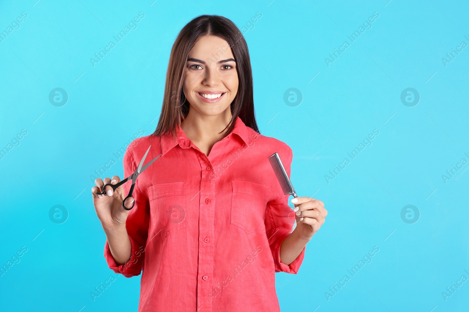 Photo of Young hairstylist holding professional scissors and comb on color background, space for text