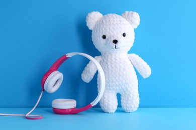 Photo of Baby songs. Toy bear and headphones on light blue background