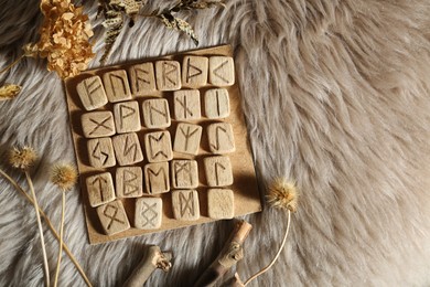 Photo of Many wooden runes and dried flowers on fur, flat lay. Space for text