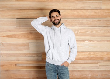 Photo of Portrait of young man in sweater at wooden wall. Mock up for design