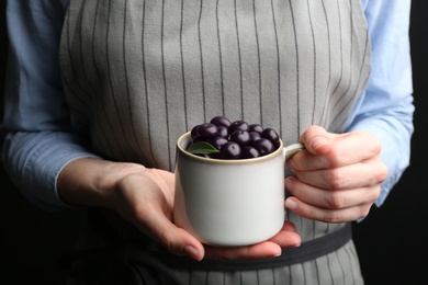 Photo of Woman holding tasty acai berries on black background, closeup