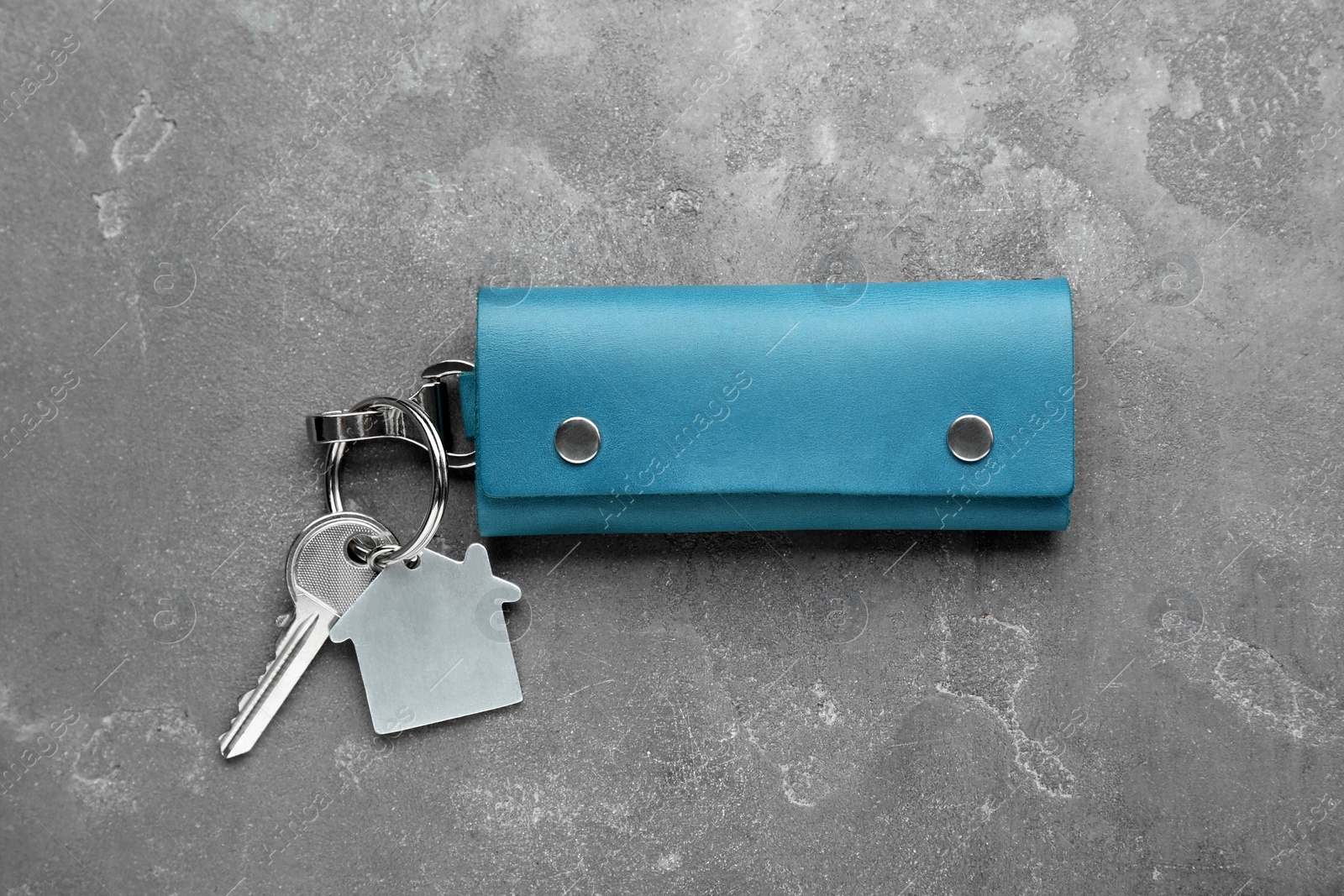 Photo of Leather case with key on grey textured table, top view.