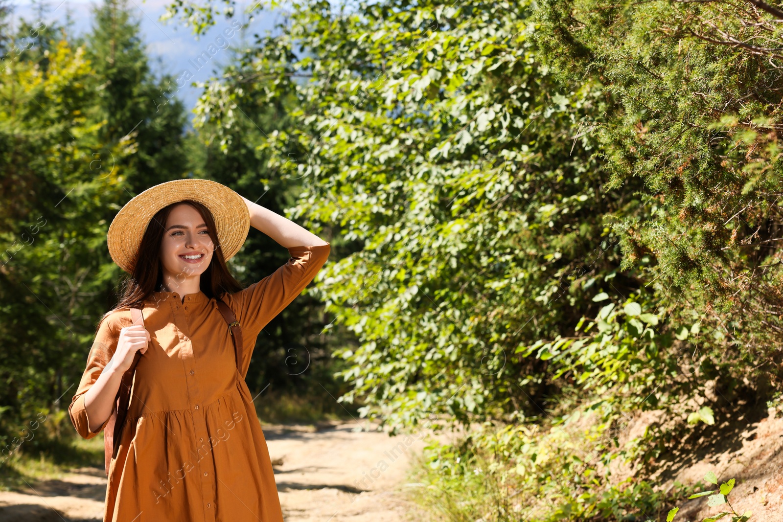 Photo of Happy woman with backpack and hat enjoying her walk in forest