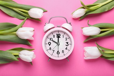 Alarm clock and beautiful tulips on pink background, flat lay. Spring time