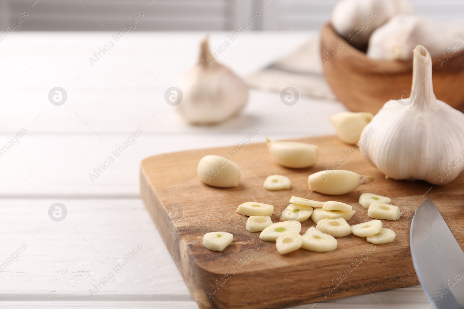 Photo of Aromatic cut garlic, cloves and bulbs on white wooden table, closeup. Space for text