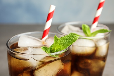 Photo of Glasses of refreshing soda drink with ice cubes and straws on blurred background