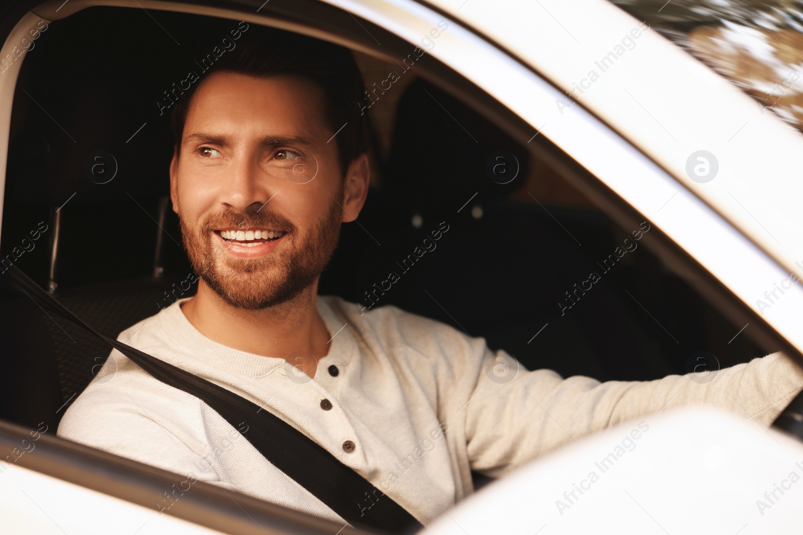 Photo of Enjoying trip. Happy bearded man driving his car, view from outside