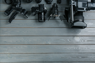 Photo of Flat lay composition with video camera and other equipment on grey wooden table. Space for text