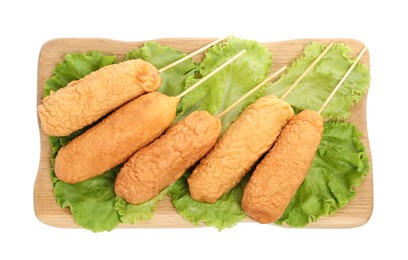 Photo of Delicious deep fried corn dogs with lettuce on white background, top view