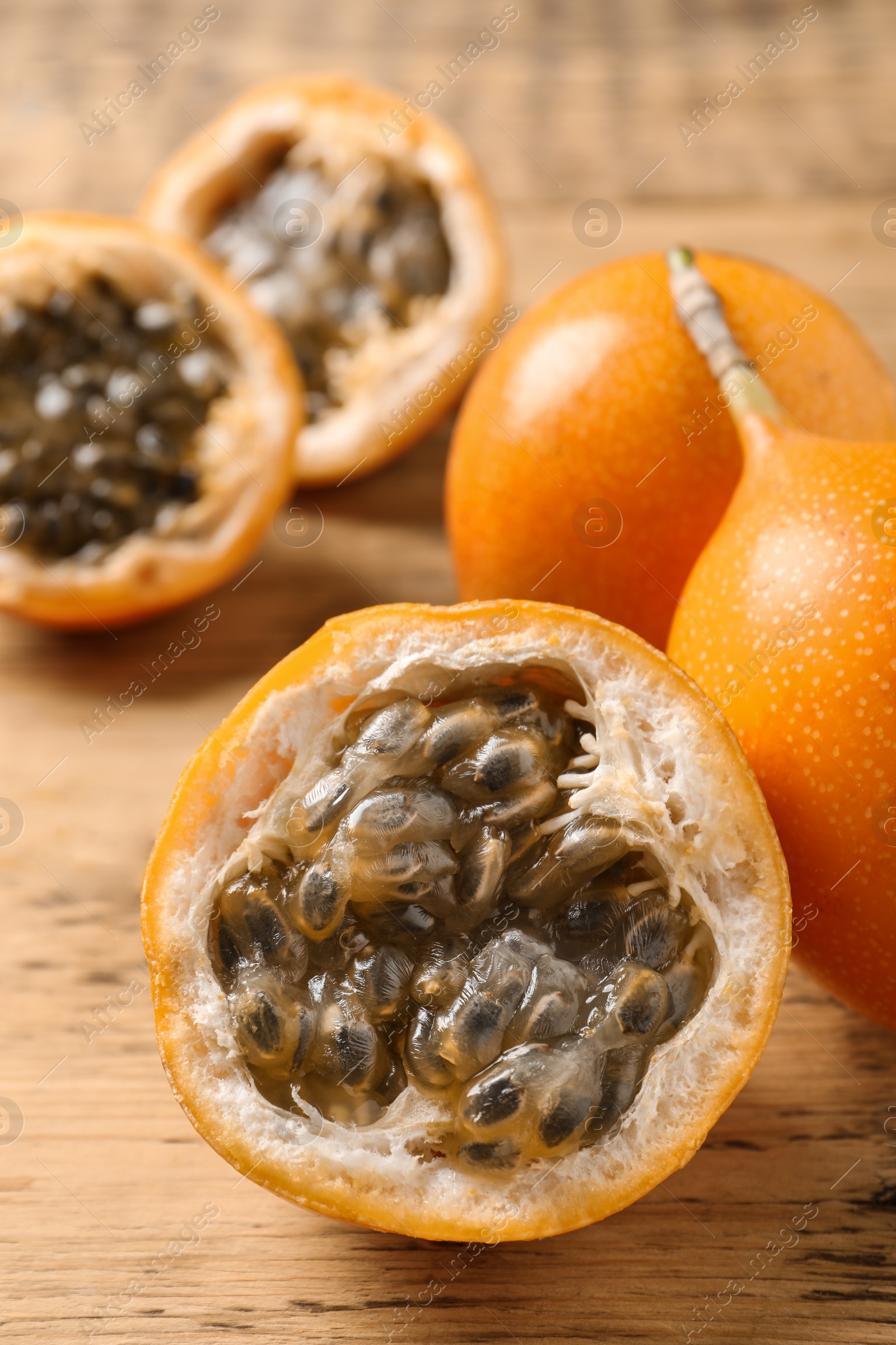 Photo of Delicious ripe granadillas on wooden table, closeup