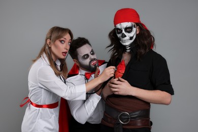 Photo of Group of people in scary costumes on light grey background. Halloween celebration