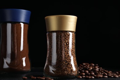 Photo of Glass jars with aromatic instant and ground coffee near beans on black wooden table