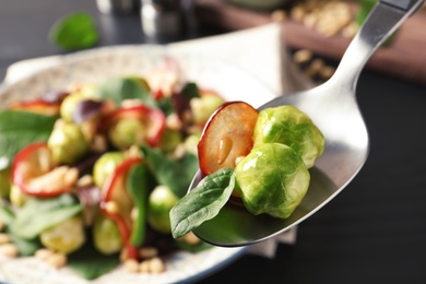 Photo of Spoon with tasty Brussels sprouts salad over table, closeup