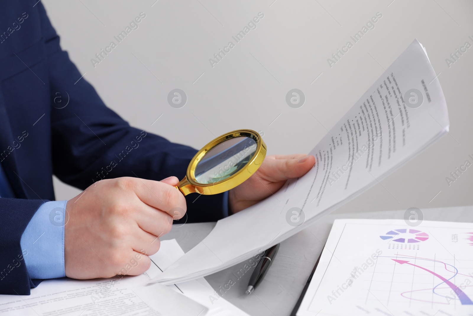 Photo of Man looking at document through magnifier at white table, closeup. Searching concept