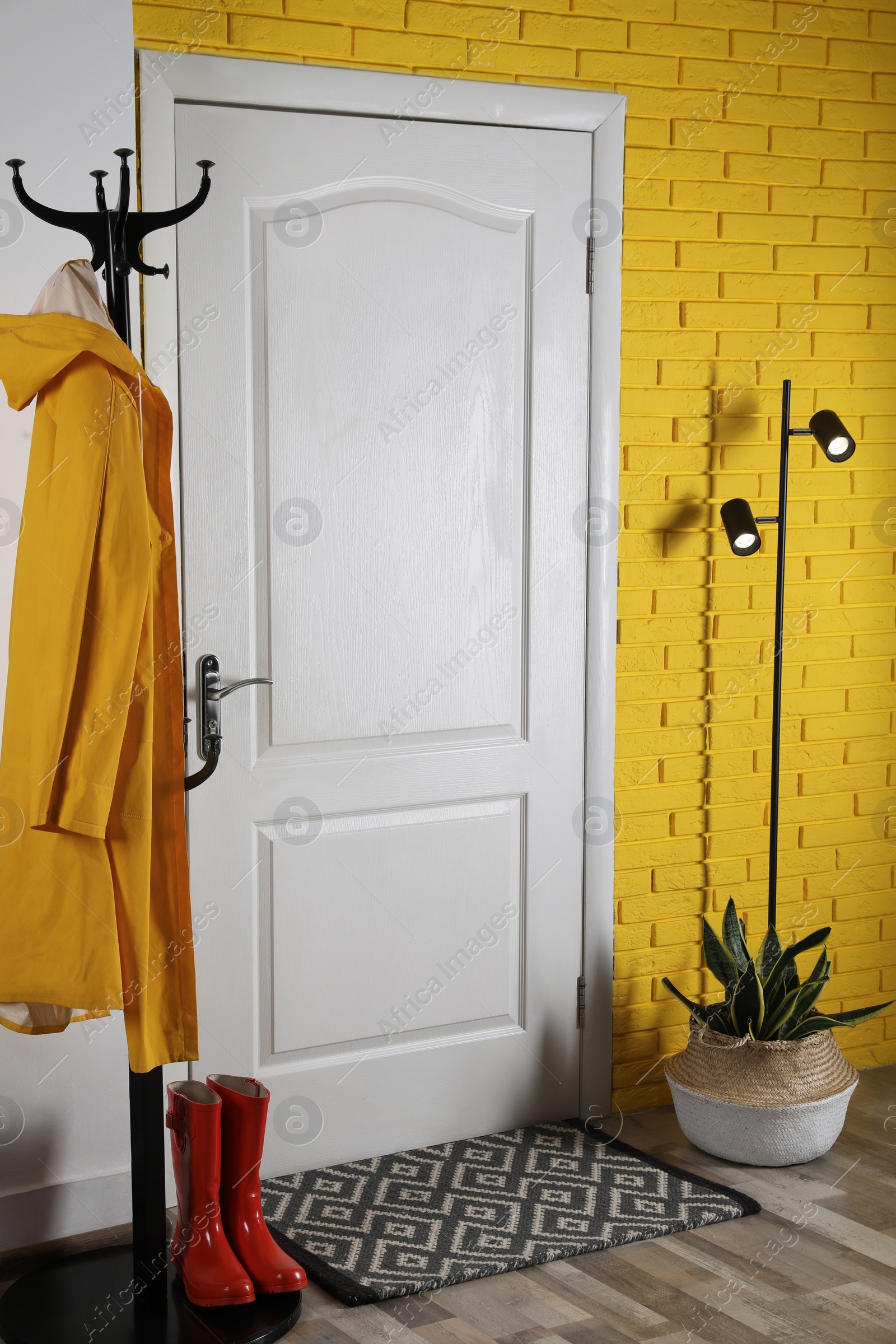 Photo of Hallway interior with beautiful houseplant, hanger stand and door mat on floor near entrance