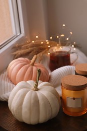 Beautiful pumpkins and candles on window sill indoors