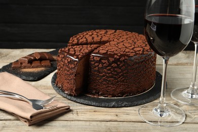 Photo of Delicious chocolate truffle cake and red wine on wooden table
