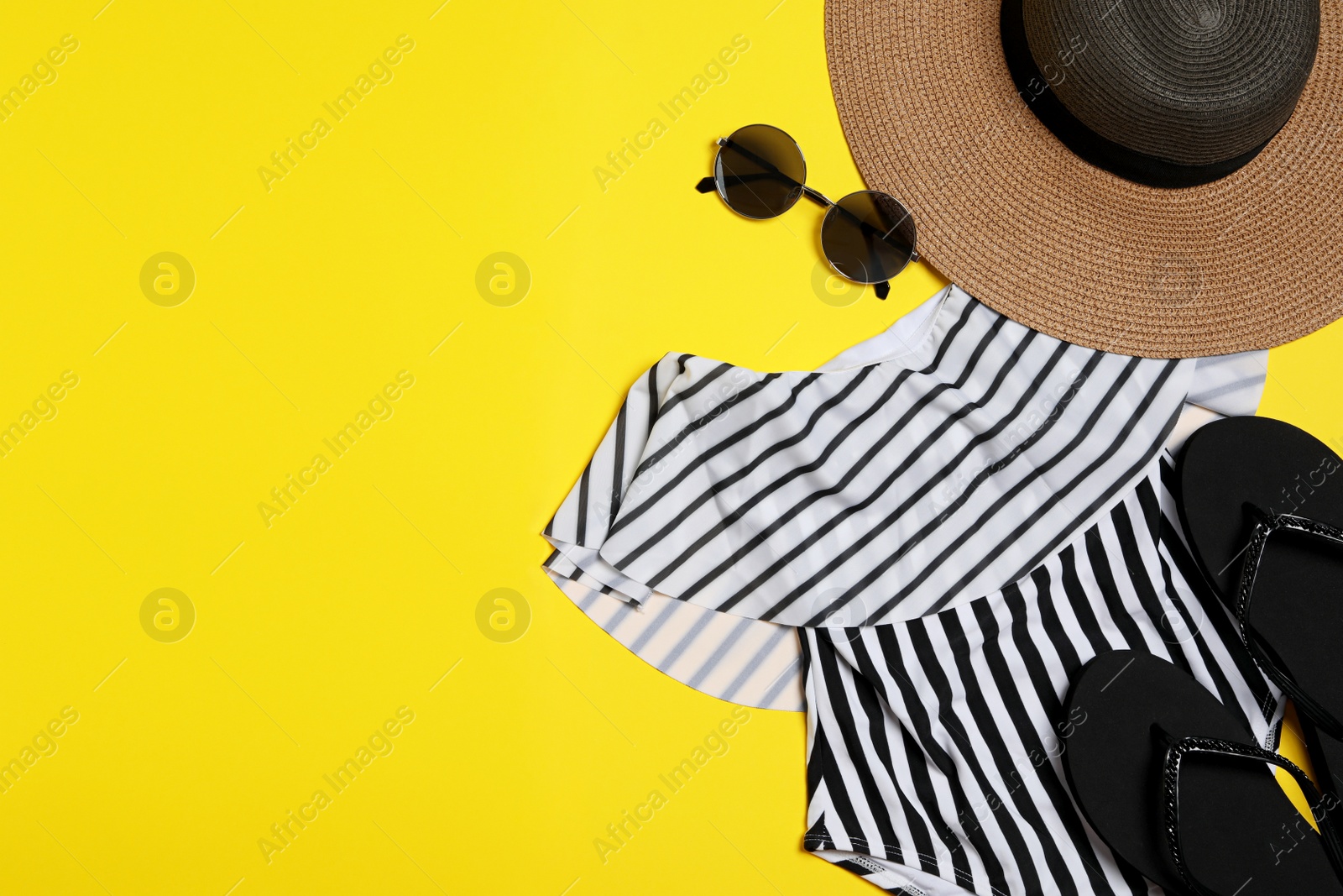 Photo of Flat lay composition with stylish beach accessories on yellow background, space for text