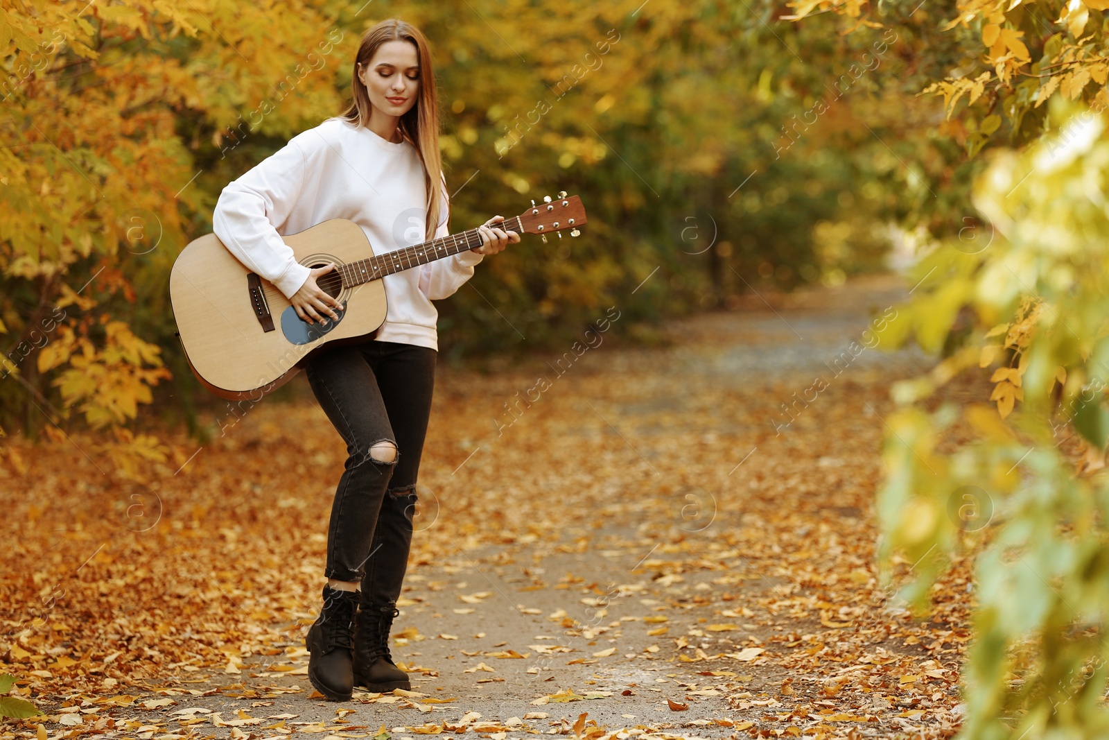 Photo of Teen girl playing guitar in autumn park