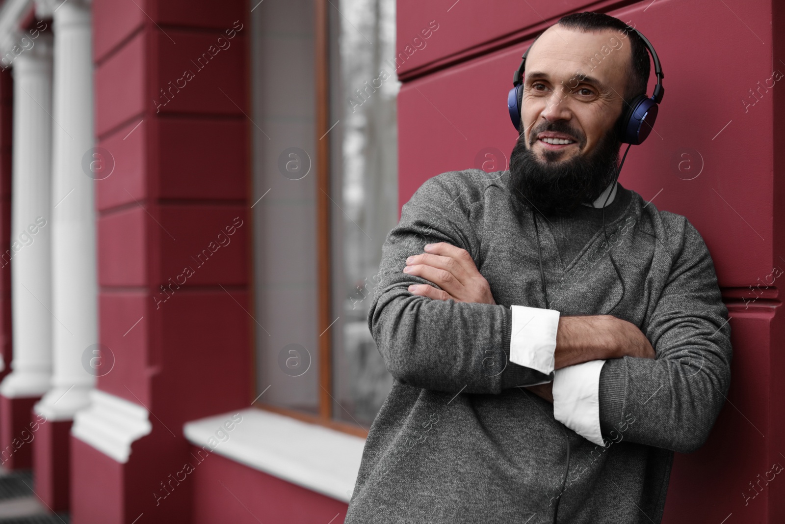 Photo of Mature man with headphones listening to music outdoors. Space for text