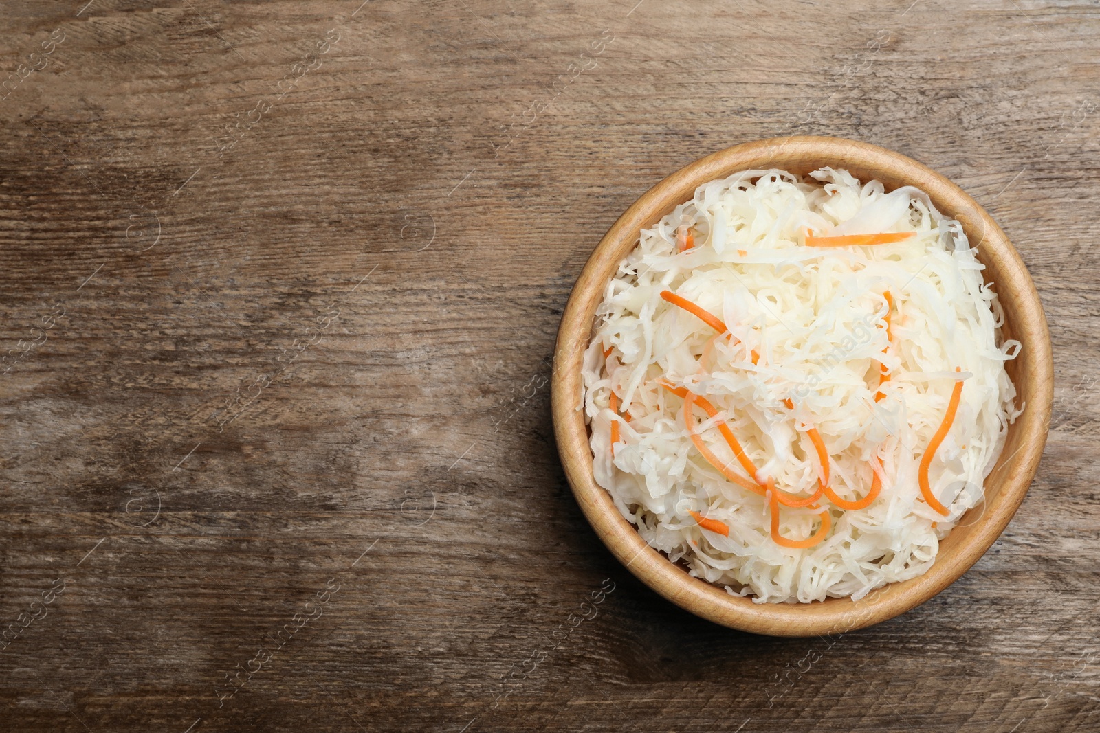 Photo of Tasty fermented cabbage on wooden table, top view. Space for text