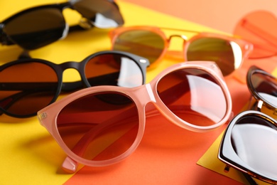 Stylish sunglasses on color background, closeup. Vacation time