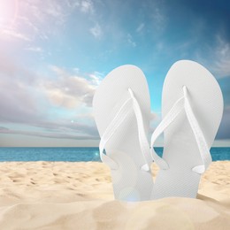 Image of White flip flops on sandy beach near sea