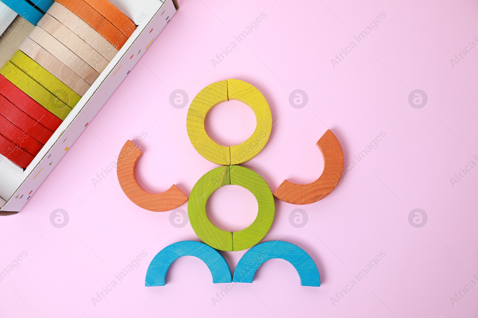 Photo of Colorful wooden pieces of playing set on pink background, flat lay. Educational toy for motor skills development