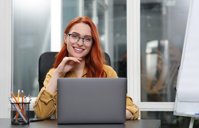 Photo of Happy woman working with laptop at desk in office