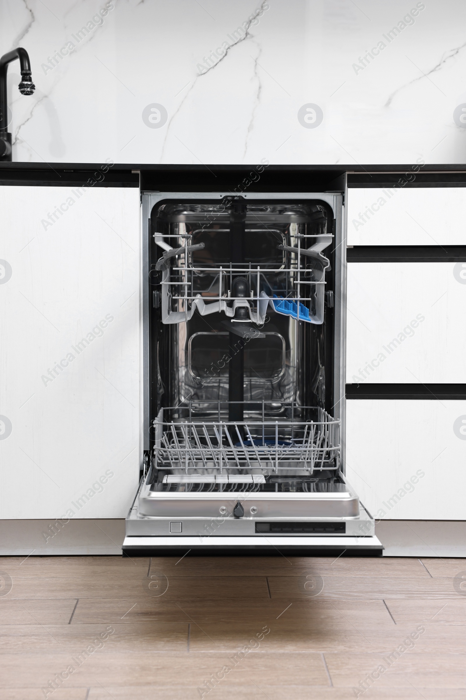 Photo of Open clean empty dishwasher in kitchen. Home appliance