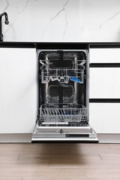 Photo of Open clean empty dishwasher in kitchen. Home appliance