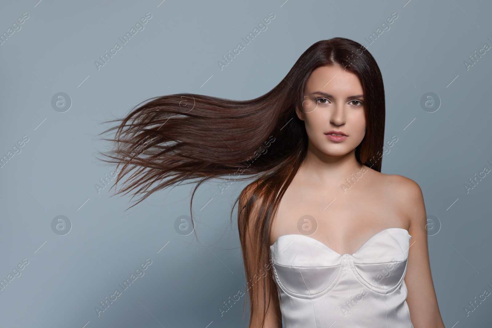 Photo of Portrait of beautiful young woman with healthy strong hair on light gray background