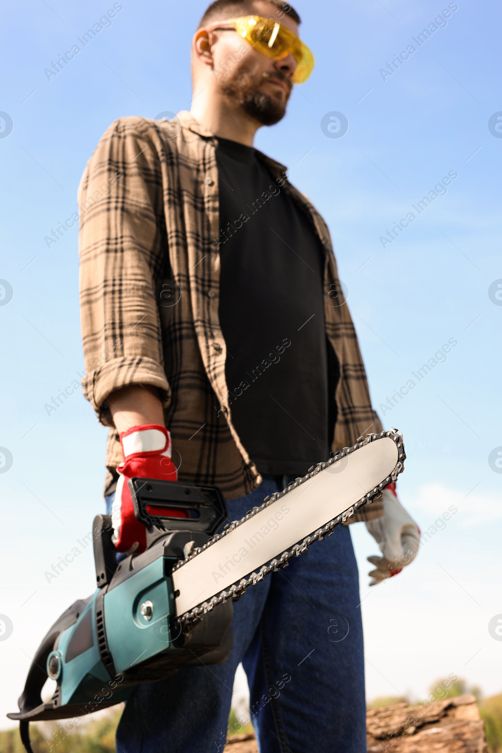 Photo of Man with modern saw against blue sky, low angle view