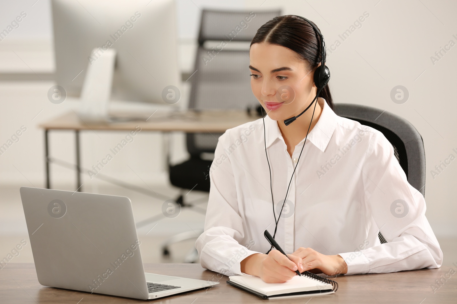 Photo of Hotline operator with headset working on laptop in office