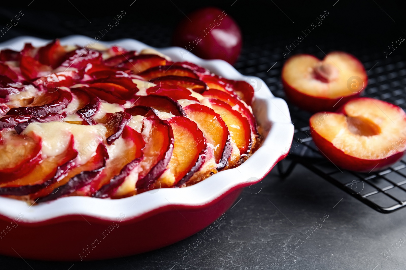 Photo of Delicious cake with plums on black table, closeup